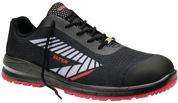 The shoe is a black, slightly sporty work shoe with gray and red accents. It has a reinforced toe cap, elastic laces, and a non-slip sole.