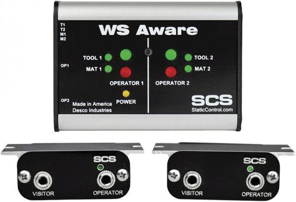 The image shows a device called "WS Aware" with a gray casing and several lights and buttons. Two black modules with sockets are placed next to it. It is used for monitoring electrostatic safety.