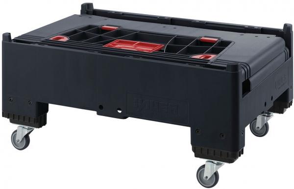 Das Bild zeigt eine rechteckige, schwarze Transportbox auf Rollen. Sie hat eine flache Oberfläche mit mehreren kleinen Fächern und einem roten Einsatzelement in der Mitte. Die Ecken sind abgerundet.