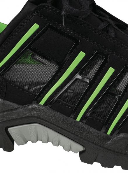 The image displays a section of a black athletic shoe with green accents. The sole is sturdy and textured, while the upper appears breathable with slight reflections.