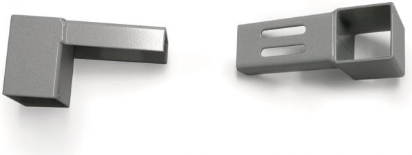Das Bild zeigt zwei metallene Teile in Grautönen. Links ein blockförmiges Element mit einer kurzen Ausbuchtung. Rechts ein langes Element mit einem quadratischen Ausschnitt und zwei schmalen Löchern.
