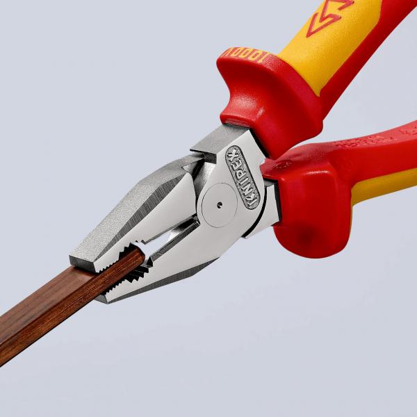 The image shows a pair of pliers with red and yellow handles. The jaws of the pliers are gripping a thick piece of wood. The background is bright and neutral, highlighting the pliers effectively.