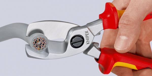The image shows a hand holding a pair of pliers. The pliers have red and yellow handles and a silver stripping surface with a special hole pattern for cutting wire.