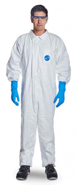 Eine Person trägt einen weißen Schutzanzug mit langen Ärmeln, blaue Latex-Handschuhe und eine Schutzbrille. Der Hintergrund ist neutral und abgedunkelt.