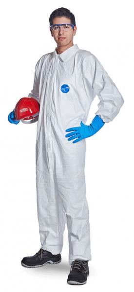 Auf dem Bild steht eine Person in einem weißen Schutzanzug mit blauen Handschuhen. Sie trägt eine Schutzbrille und hält einen roten Helm in der linken Hand.