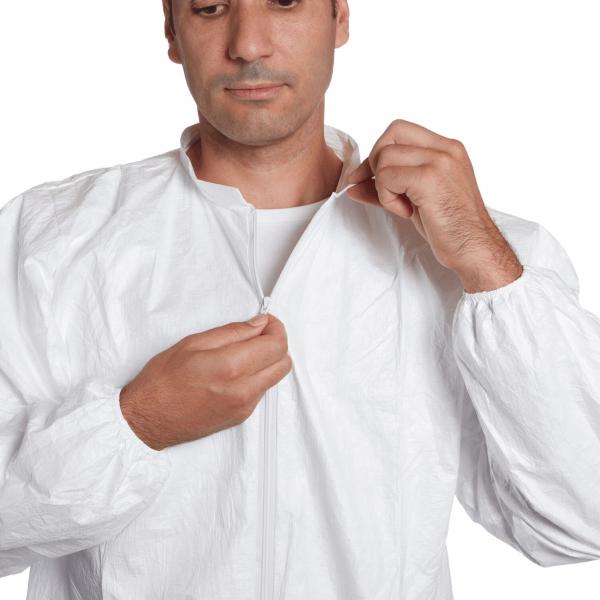 A man is wearing a white jumpsuit with a zipper. He is slightly leaning forward and pulling the zipper up with both hands.