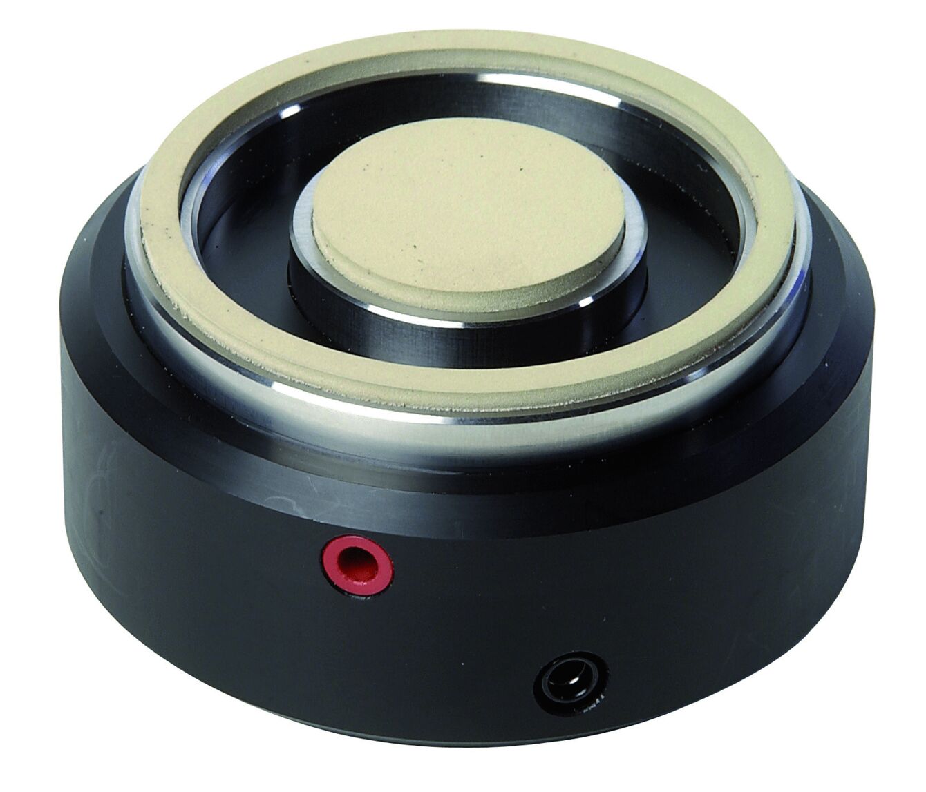 The image shows a round, black component with a central, flat element made of lightweight material. It has a red and a black connector on the side. This component could be part of a speaker or similar device.