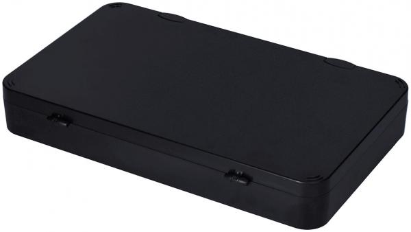 The image shows a flat, rectangular box in black. The top is smooth and has rounded corners. On the sides, two small indentations are visible, likely for opening.