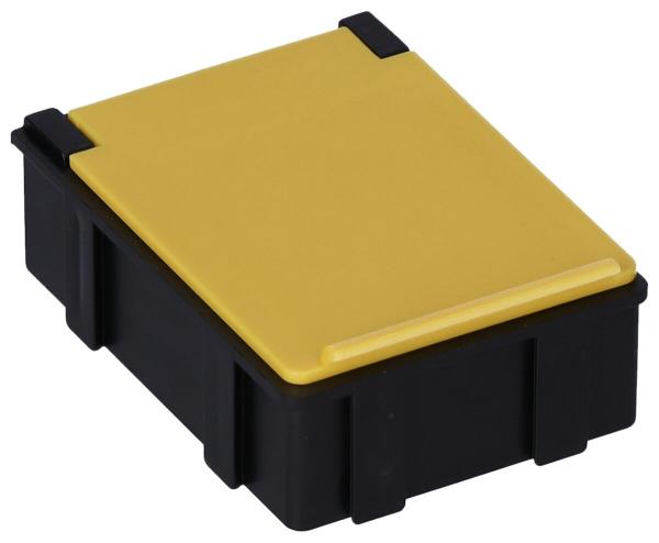 The image shows a small, rectangular box. The body is black and has a yellow, flat top. The corners are rounded, and there are side indentations. The box appears sturdy and practical.