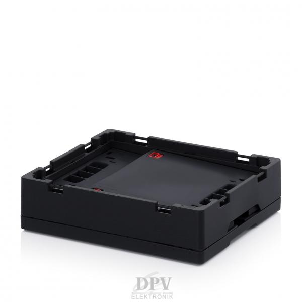Das Bild zeigt eine schwarze, quadratische Elektronikbox mit leicht erhöhten Kanten. Die Oberfläche ist schlicht und matt, mit Aussparungen an den Seiten. Der Hintergrund ist weiß.