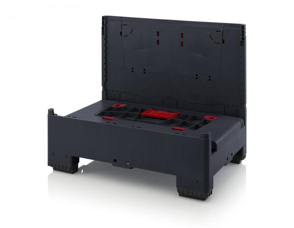 Das Bild zeigt eine schwarze, rechteckige Box mit einem aufklappbaren Deckel. Im Inneren sind rote und schwarze Einsatzmöglichkeiten für Werkzeuge oder Zubehör sichtbar. Die Box wirkt stabil und funktional.