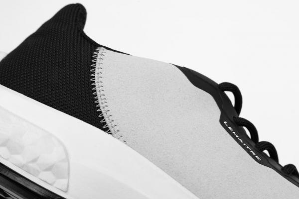 Das Bild zeigt einen sportlichen Schuh mit einer grauen und schwarzen Oberfläche. Der Schuh hat eine bequeme, gepolsterte Sohle und eine moderne, schlanke Form, ideal für Bewegung und Fitness.