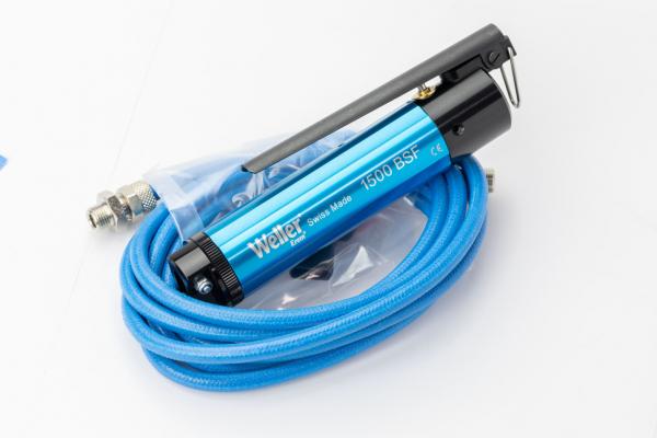 Auf dem Bild ist ein Werkzeug zu sehen: Ein blauer Heißluftfön mit einem schwarzen Griff und einem Schlauch. Der Schlauch ist ebenfalls blau und gewunden. Das Gerät hat eine metallische Düse.