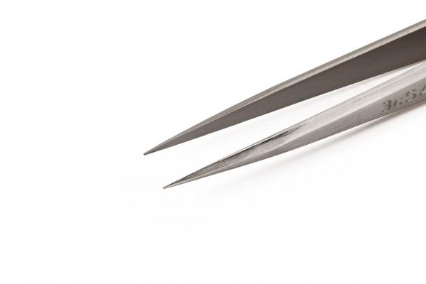 The image shows a sharp metal scissors with long, narrow blades. The silver surface lightly reflects the light. It is lying on a white background.