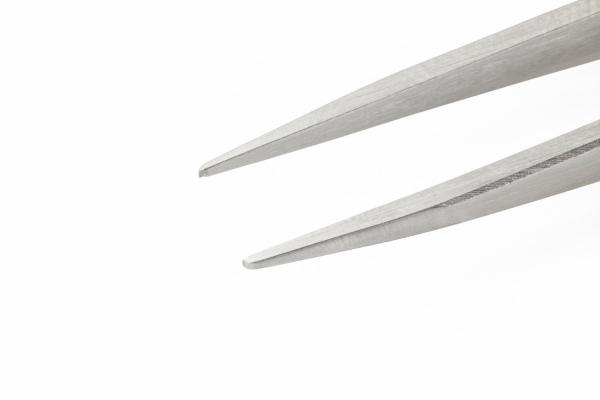 The image shows a narrow, shiny tweezer with pointed tips. The background is light and solid, making the tweezer stand out clearly.