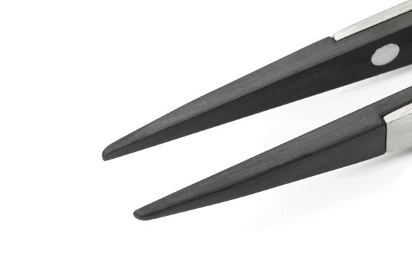 The image shows the tips of a pair of scissors. The blades are narrow and pointed, with a shiny silver surface and a matte, black coating on the edges.