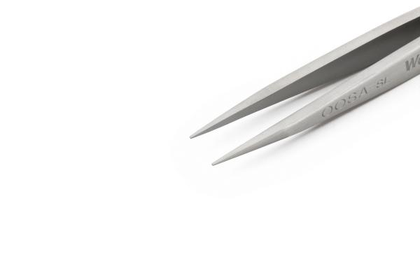 The image shows a metallic tweezer with long, pointed tips. The surfaces are shiny, and the tweezer is lying on a bright, solid-colored background.