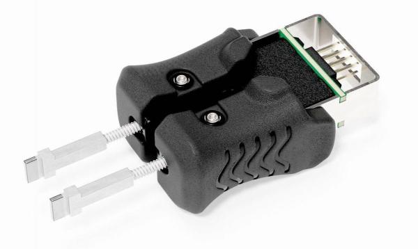 Das Bild zeigt ein schwarzes Gerät mit zwei seitlichen Hebeln und einer Anschlussbuchse. Es hat eine ergonomische Form und zeigt technische Details für die Verbindung oder Anpassung von Kabeln.
