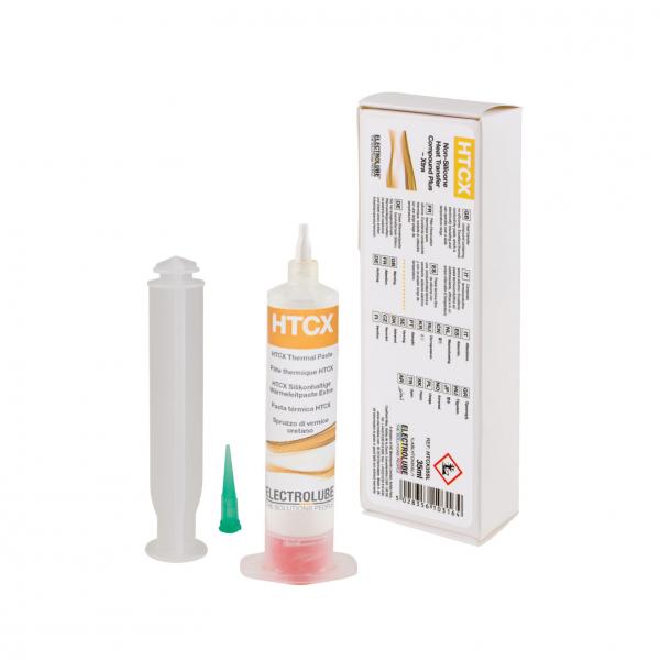The image shows a tube with orange and white lettering containing a yellowish liquid. Next to it is a gray syringe and a small green tip. In the background, there is a white package with information and warning labels.