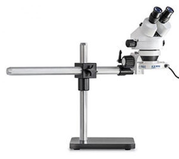 The image shows a microscope on a stable base. It has two eyepieces and a long, horizontal arm for viewing objects. The colors are primarily white and gray.