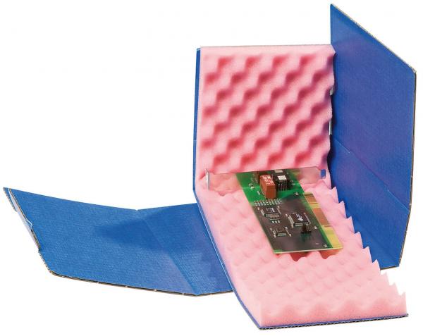 The image shows an open cardboard box with a blue exterior and pink foam inside. Inside lies an electronic circuit board. The foam is meant to protect the circuit board.