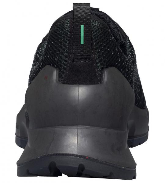 Das Bild zeigt die Rückansicht eines schwarzen Sportschuhs. Die Sohle ist robust und hat ein griffiges Muster. Am Schuh befindet sich ein grüner Streifen oben in der Mitte.