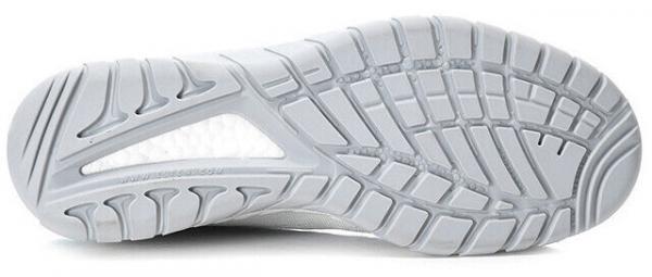 The image displays the sole of a white sports shoe. The sole features a textured pattern with grooves and studs that provide grip and traction.