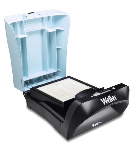 The image shows a black device with an open, light blue lid. Inside, there is an empty space apparently intended for books or documents.
