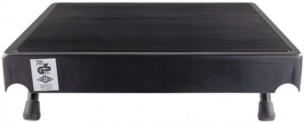 The image shows a black, rectangular platform with a slightly textured surface. It stands on four short legs and has rounded corners. A certificate is attached.
