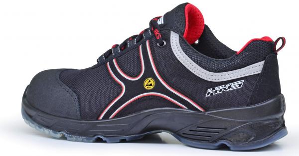 The shoe is a black sneaker with red and silver accents. It has a sturdy sole, laces, and is designed for safety and comfort.