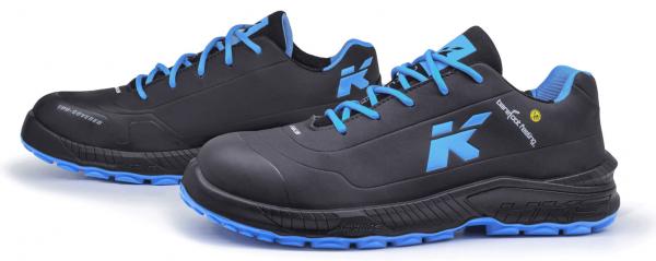 The image shows a pair of athletic shoes in black with blue shoelaces. On the side, there is a large, light blue "K" displayed. The sole is also designed in blue.