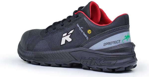 Der Schuh ist ein schwarzer Sneaker mit roten Akzenten. Er hat ein sportliches Design, ein verstärktes Profil und eine rutschfeste Sohle. Auf der Seite sind Logos und Hinweise auf die Technologie.