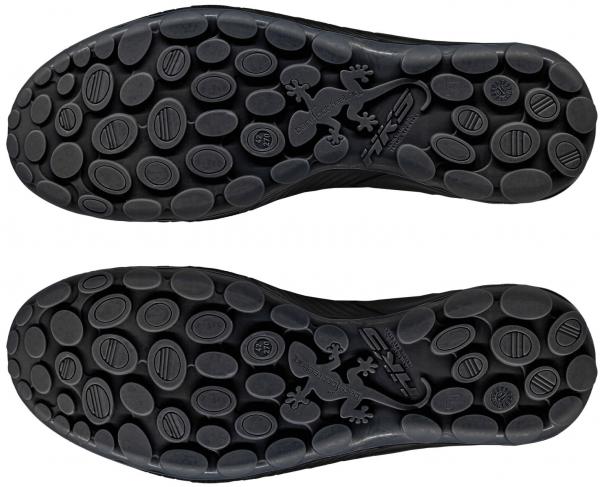 Das Bild zeigt die Sohle von zwei Schuhen. Sie sind schwarz mit vielen kleinen runden Noppen und einem geprägten Gecko-Motiv in der Mitte. Die Sohle hat einen flexiblen und rutschfesten Look.