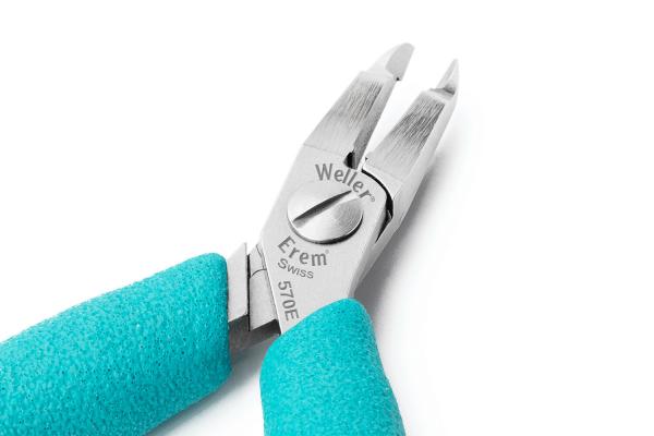 The image shows a pair of pliers with fine, sharpened blades. The grip surfaces are made of gray, non-slip material and have a turquoise coating.