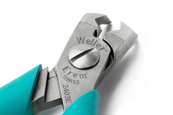 The image shows a silver pair of pliers with a special cutting surface. The handles are in a light turquoise. Markings are engraved into the pliers. It appears precise and sturdy.