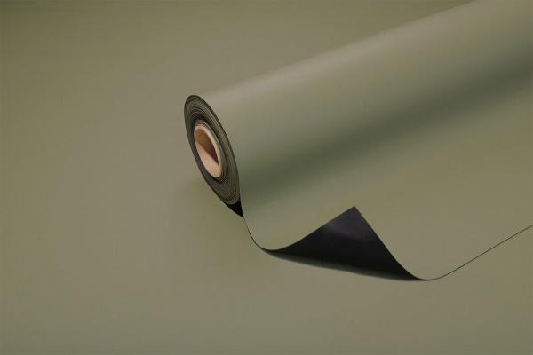 The image displays a roll of olive green paper, partially unrolled. The surface is matte shimmering, and the underside is black. The background is uniform and harmonious.