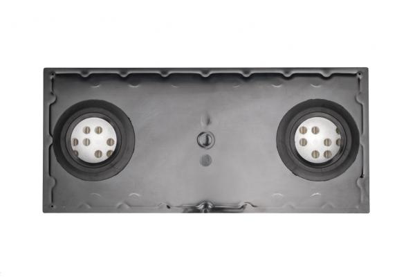 The image shows a rectangular, black plastic surface with two round openings on the sides. In the center, there is a small, round button. The surface is smooth and solid-colored.