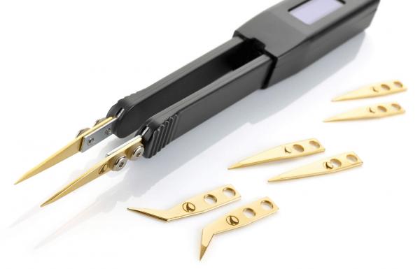 In the image, there is a black electronic tweezer with two pointed gripping arms and several small, golden cutting blades. The blades are of various shapes.