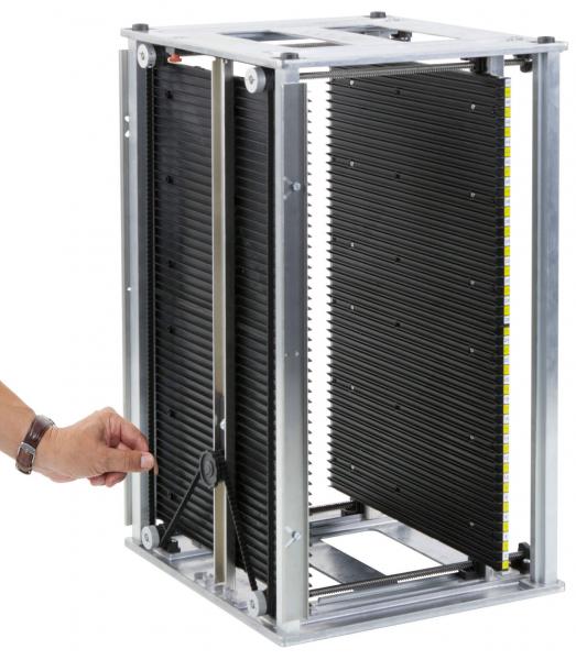 Das Bild zeigt ein quadratisches, offenes Gerät aus Metall mit beweglichen schwarzen Platten. Eine Hand greift an einer Seite, um die Platten zu bewegen. Es wirkt wie ein Modul zur Licht- oder Luftregulierung.