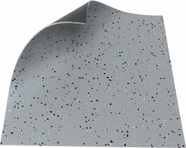 The image displays a piece of light gray flooring with colorful, irregular dots in blue and white. One corner is flipped up, revealing the structure.
