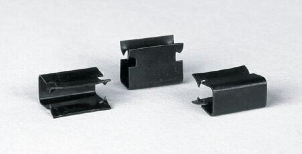 In the image, there are three black metal brackets visible. They have an oval shape with notched sides and an opening in the middle. The brackets are lying flat on a light surface.