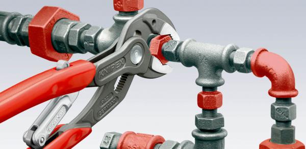 Das Bild zeigt eine Kombination aus Metallschläuchen, -anschlüssen und einer verstellbaren Zange. Die Zange ist rot, die Rohrverbindungen bestehen aus grauem und rotem Metall.