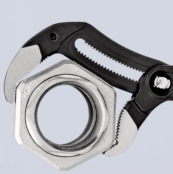 The image shows an adjustable wrench gripping a metal nut. The wrench has grippy, black handles and sharp teeth for better handling.