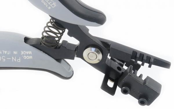 The image shows a pair of pliers with a curved, gray surface and a spring. The pliers have two jaws, one of which is equipped with a small trigger.
