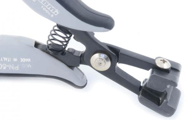 The image shows a gray, ergonomic pliers with a spring. The pliers have a simple, functional shape and a black holder with a fastening element.