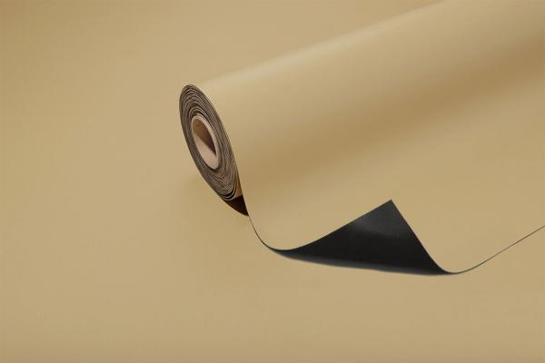The image shows a roll of paper-like material in light beige, partially unrolled. The underside is black, and the edge of the paper is slightly wavy.