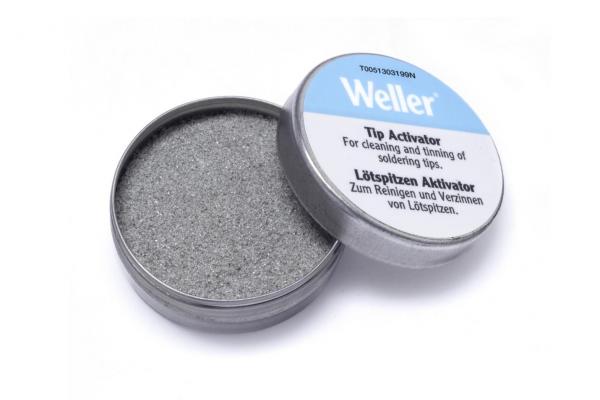 Es handelt sich um eine runde, flache Metalldose, die geöffnet ist. Der Inhalt ist graues Pulver auf der Innenseite. Der Deckel ist mit der Aufschrift ?Weller Tip Activator? versehen.