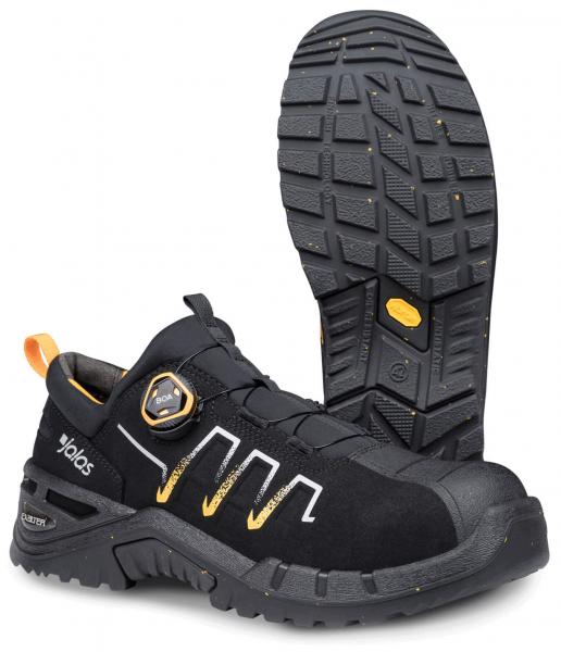 Der Schuh ist schwarz mit grauen und gelben Akzenten. Er hat eine robuste, gestoßene Vorderseite, eine rutschfeste Sohle und ein schnelles Schnürsystem mit einer runden Schnalle.