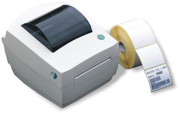 The image shows a white label printer with a glossy lid and a green button. Next to it is a roll of white labels that is being unrolled.