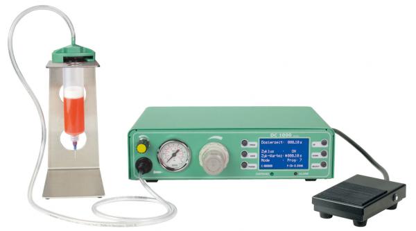 The image shows a medical device with a green casing and a digital display. Next to it is a transparent container with red liquid and a foot pedal.